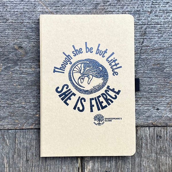 Notebook with 'Though she be but little, she is fierce' quote on a wooden surface