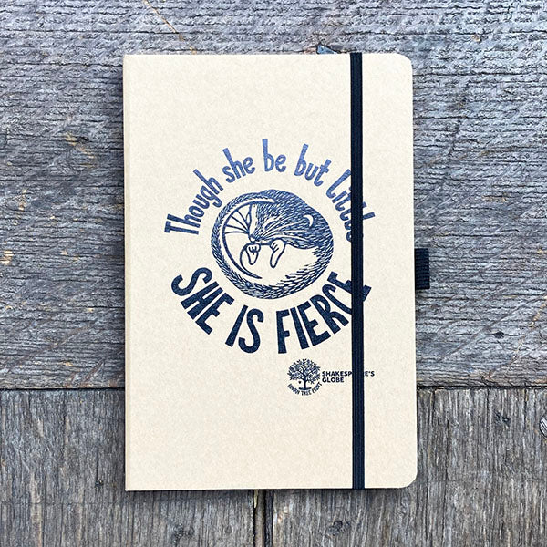 Notebook with 'She is Fierce' design on a wooden surface