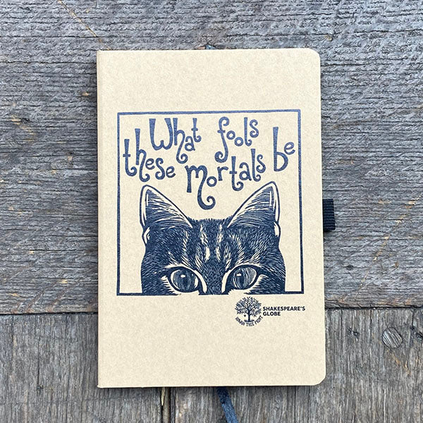Notebook with a cat illustration and text on a wooden surface