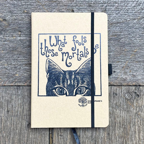 Notebook with a cat illustration and text on a wooden surface