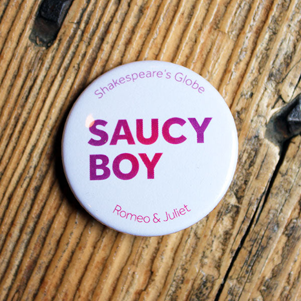 white button badge with purple-pink text lying on a wooden bench