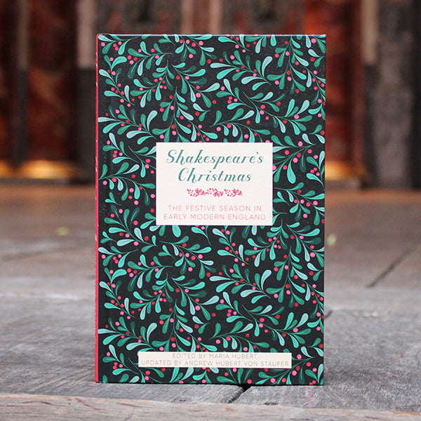 Book titled 'Shakespeare's Christmas' with a green and pink leaf pattern on a wooden surface.