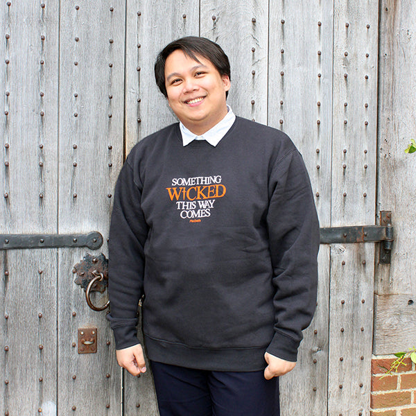 Black cotton sweatshirt with white graphic font across the centre front and 'Wicked' text in orange