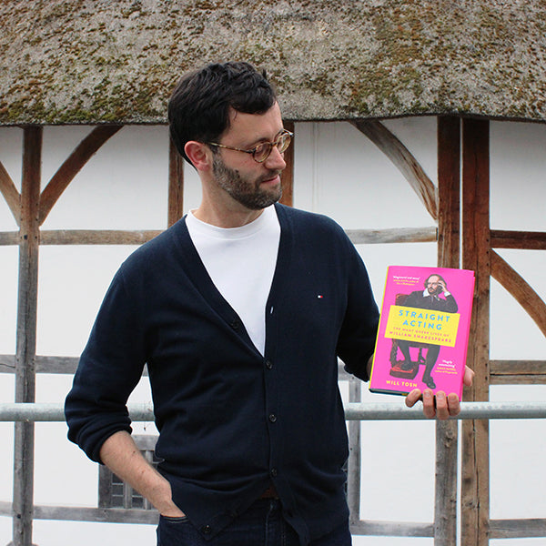 Dr Will Tosh holding a book titled 'Straight Acting' in front of the Globe Theatre