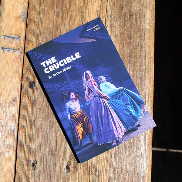 paperback book with a blue cover lying on a wooden bench