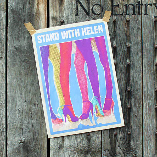 Art print with colorful legs and 'Stand With Helen' text on a wooden background