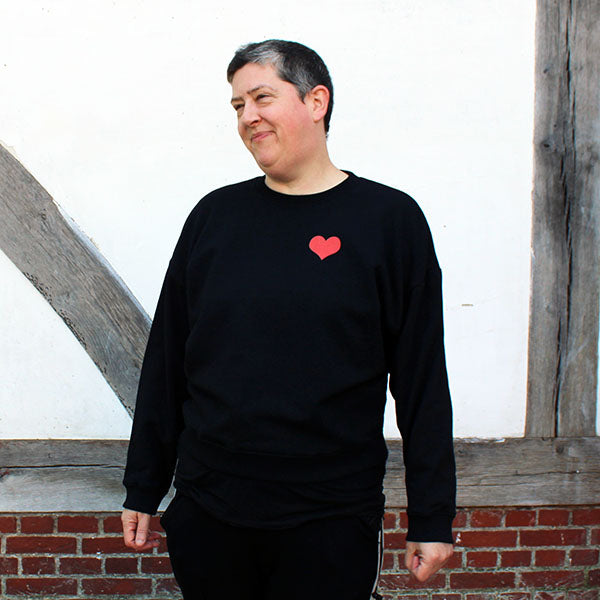 Black boxy fit cotton sweatshirt with small red heart graphic on upper left chest