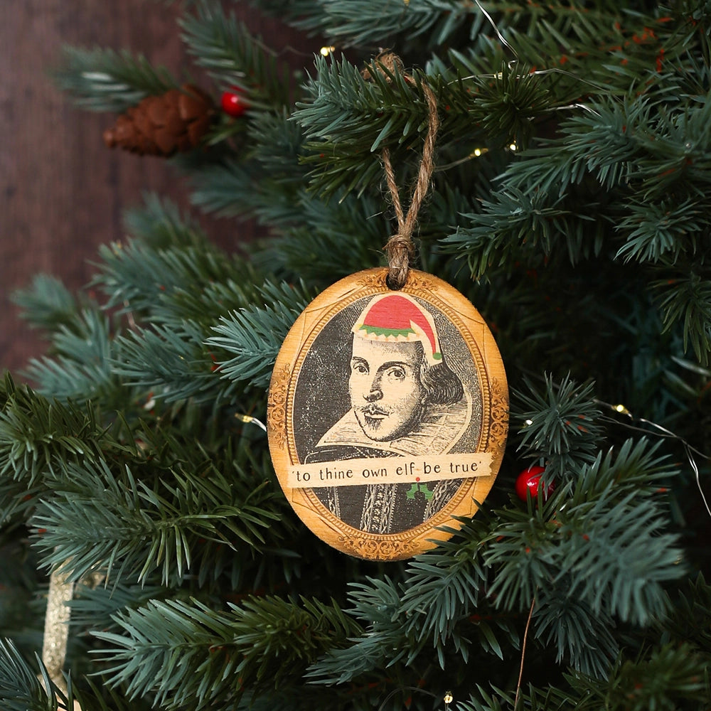 Wooden oval decoration with black portrait and cartoon red santa hat, on Christmas tree