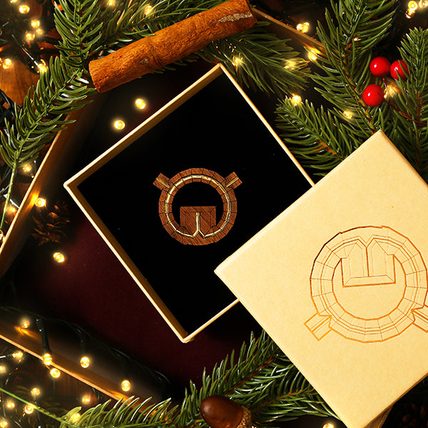Gift box with a logo surrounded by Christmas decorations on a dark background