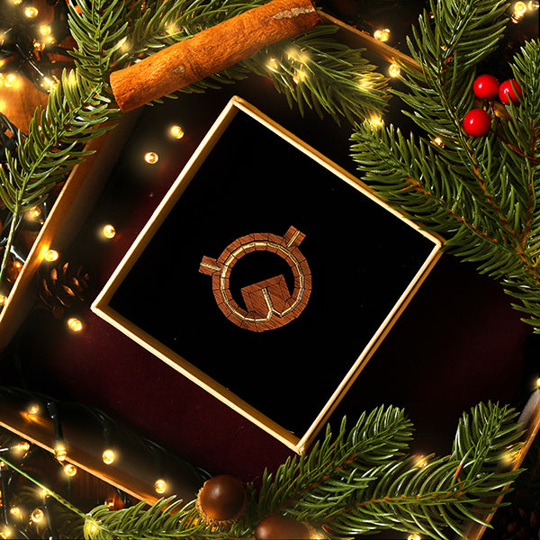 walnut wood brooch of the Globe Theatre in plan view in a gift box surrounded by festive greenery