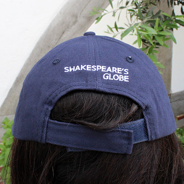 Navy blue six panel baseball cap with an embroidered motif in white across the back closure