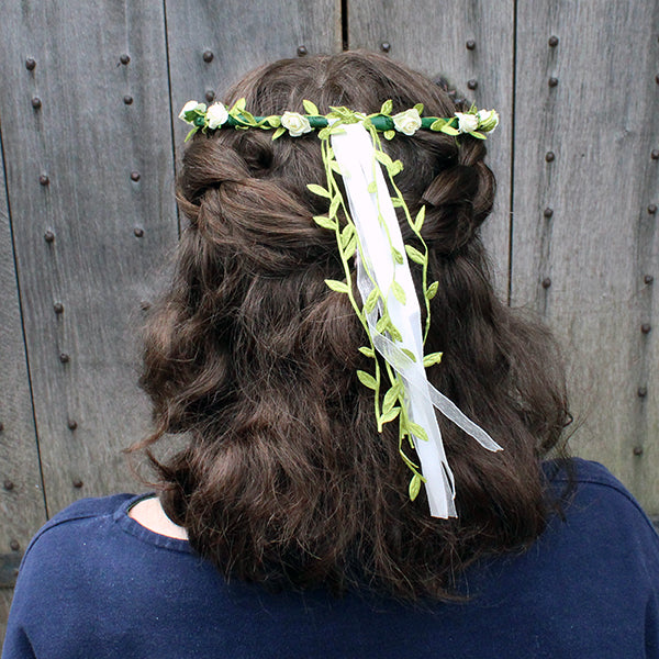 Faux flower, flower crown with greenery and white flowers and ribbons on brunette shoulder length wavy hair