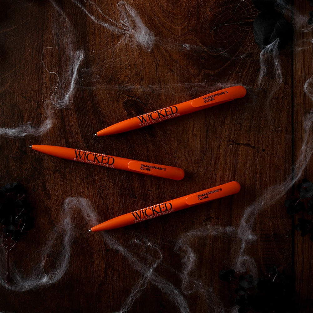 Orange bioplastic ballpoint pen printed on the barrel with a quote from Shakespeare play, Macbeth, "Something wicked this way comes", in black and white lettering