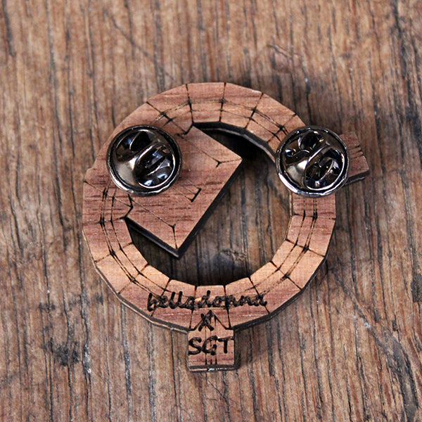 The back of a wooden brooch with two butterfly clutch clips attached