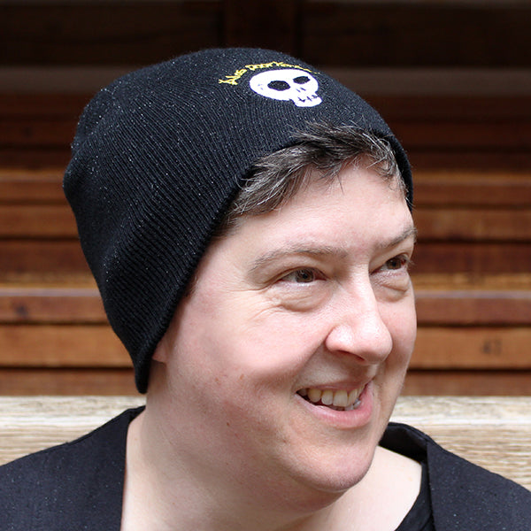 Black knit beanie with embroidered skull with graphic gold text above