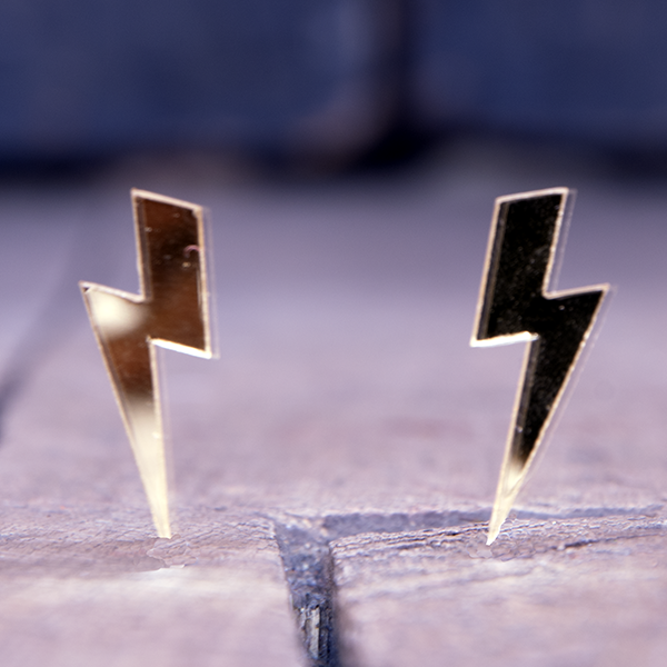 Acrylic earrings in the shape of lightning bolts. Gold mirror effect.