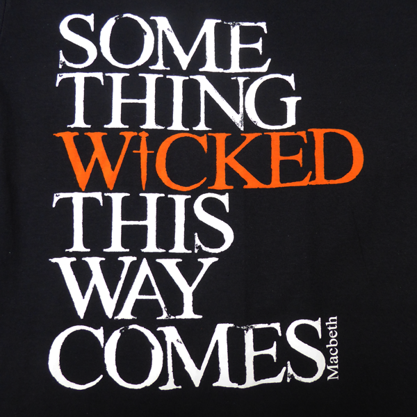 Black cotton crew neck, short sleeve t-shirt with a quote from Shakespeare play, Macbeth printed on the chest. The quote is printed in white, slightly distressed capital letters with the word 'wicked' printed in bright orange.