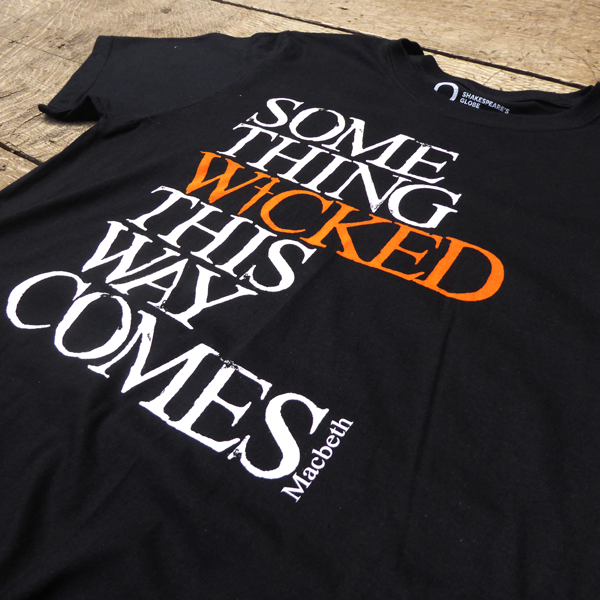 Black cotton crew neck, short sleeve t-shirt with a quote from Shakespeare play, Macbeth printed on the chest. The quote is printed in white, slightly distressed capital letters with the word 'wicked' printed in bright orange.