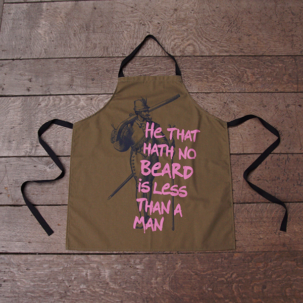 Olive green cotton apron with black neck loop and ties. The apron is printed with an etching in black of a man in Stuart dress and a fine beard. Over this is printed a quote from Shakespeare play, Much Ado About Nothing, 