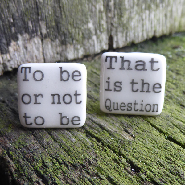 Square ceramic cufflinks made of creamy white glazed earthenware. Each cufflink has part of a quote from Shakespeare play, Hamlet in black in a simple serif font. One cufflink says