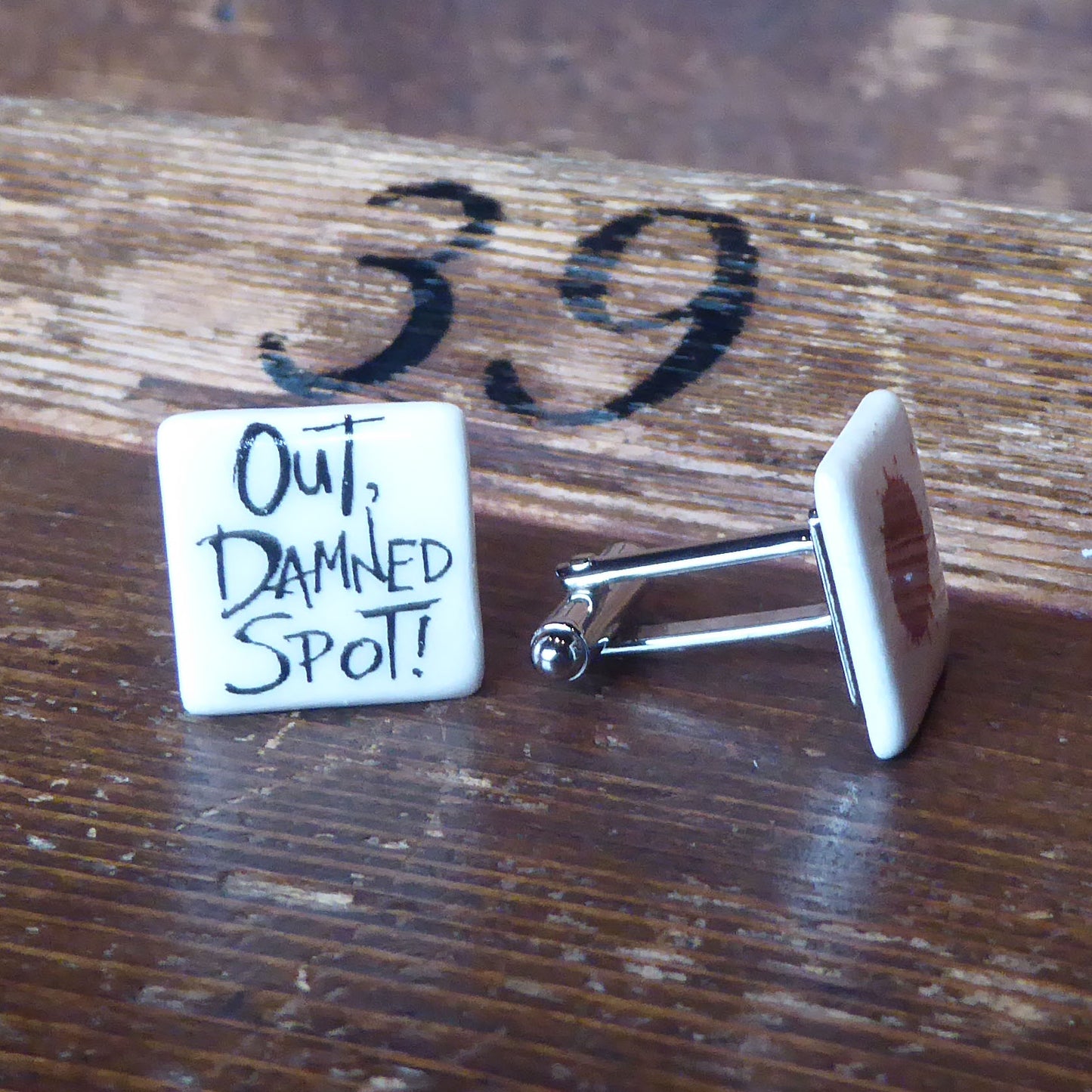 Ceramic cufflinks featuring a quote from Lady Macbeth on one (Out, damned spot!) and a blood spot on the other