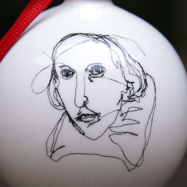 White fine china hanging bauble with a gold ferule and red ribbon. On the bauble is a portrait of William Shakespeare based on an embroidery. The portrait is made up of black lines and has a scribbled look.