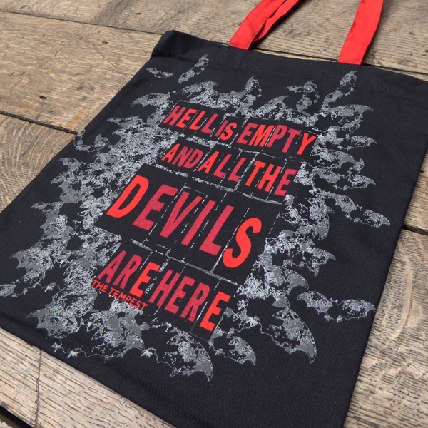 Black cotton bag with red mid-length handles. The bag is printed with a quote from Shakespeare play, The Tempest (Hell is empty and all the devils are here) in bold, san serif, capital letters. Surrounding the quote is a cloud of grey bats flying out as if from hell.