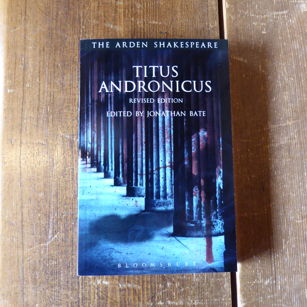 Moody blue scene showing columns in a vertical row, with blood dripping down the top right of paperback book cover