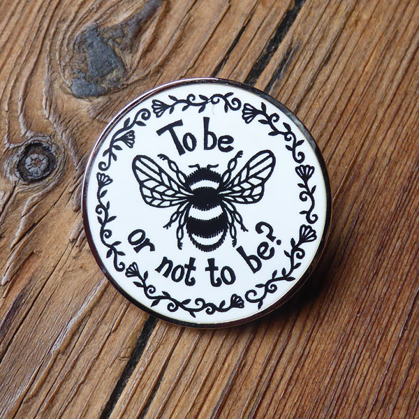 White circular pin badge with black graphic bee and text