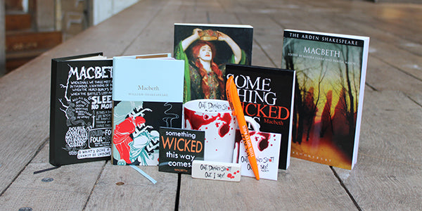 Grouping of Macbeth texts with white china mug and orange pen on wooden stage