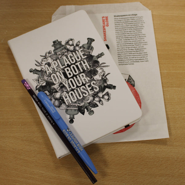 
                  
                    White paper bag with white hardback notebook, and purple pencil and blue pen sitting on top
                  
                