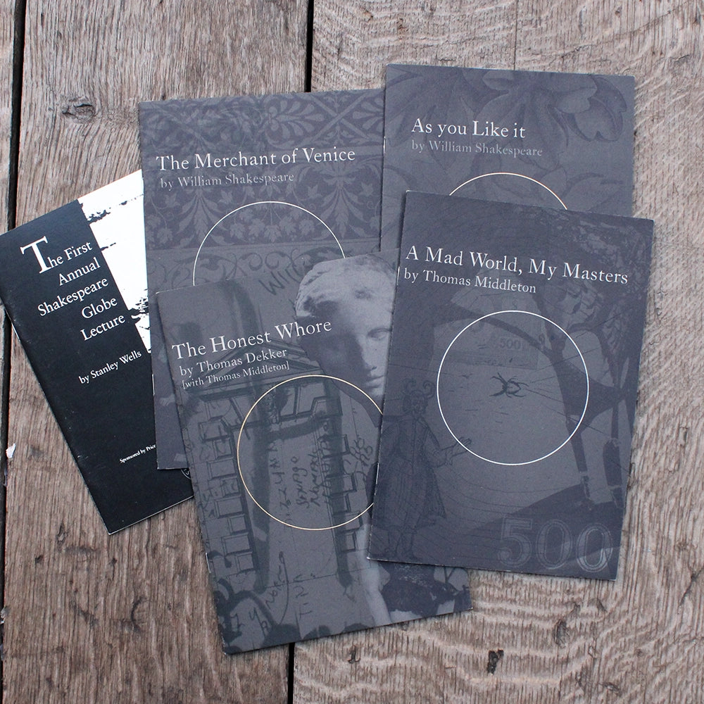 Four theatre programmes with dark grey covers on a wooden background