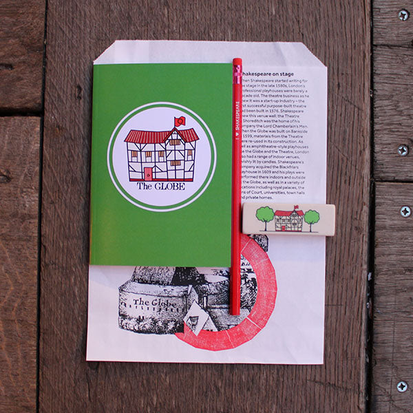 
                  
                    White paper bag with black text, with a green paperback notebook, white eraser and red pencil sitting on it
                  
                