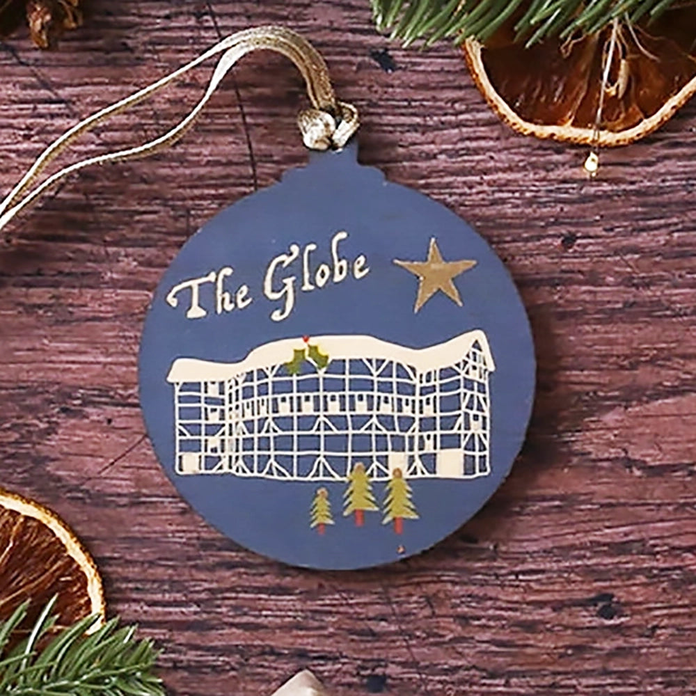 Blue round wooden decoration with 'The Globe' and stylised drawing of the Globe Theatre on wooden background with Christmas greenery