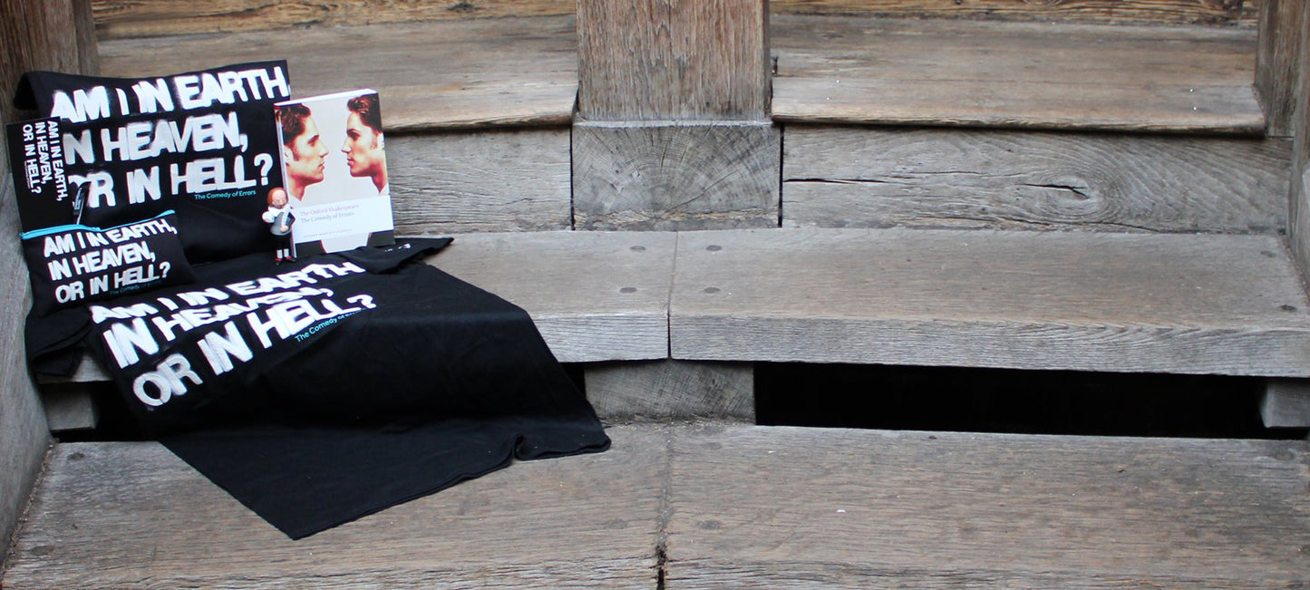 Black t-shirt, tote bag and pencil case with stylised white graphic text sitting next to white paperback book with identical twins on the cover