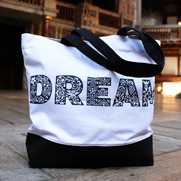 
                  
                    White cotton tote bag with black base, black DREAM text, and two black handles on Globe stage
                  
                