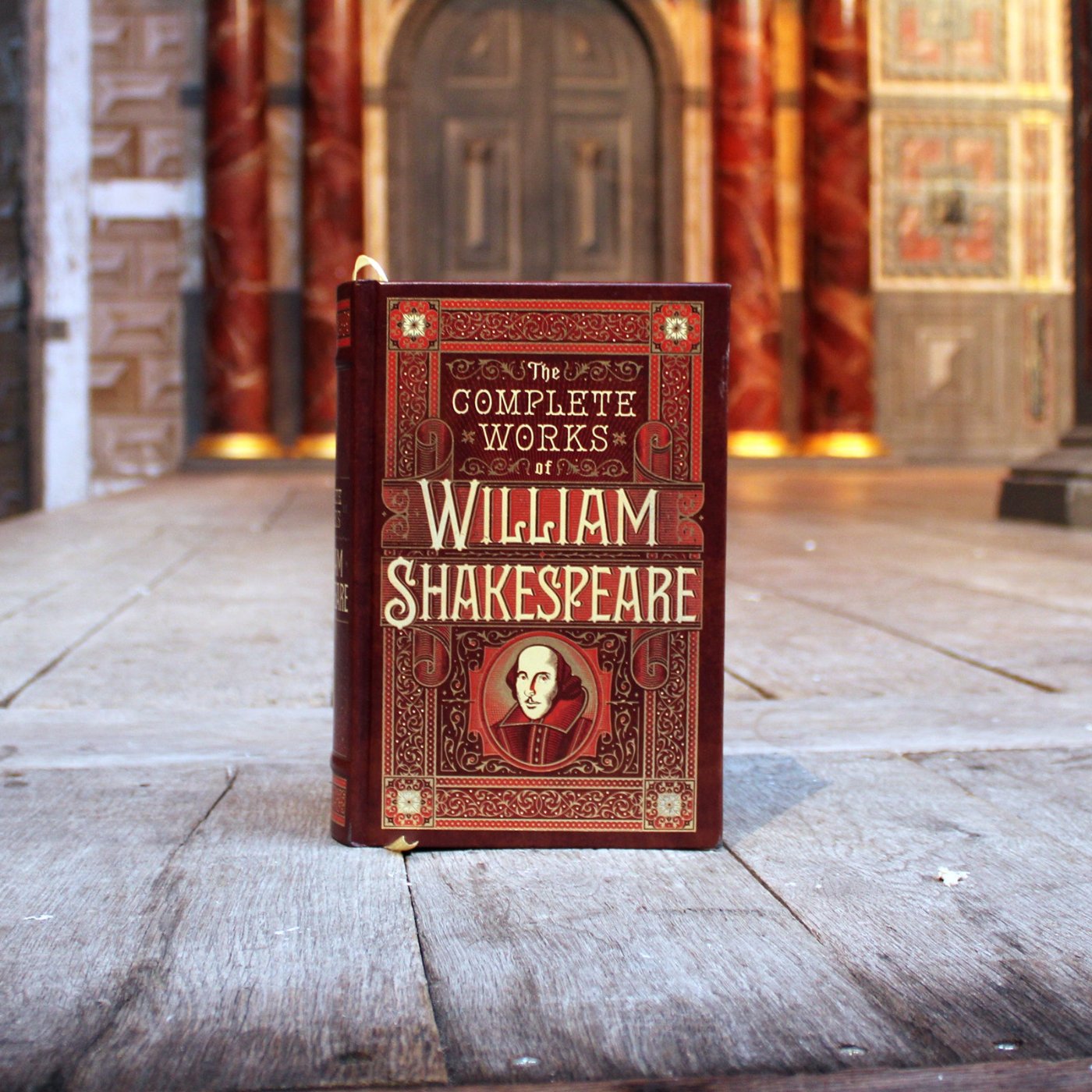 Brown leather, hardback book with beige and gold text and Shakespeare motif on the centre front