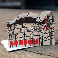 Die cut Christmas card featuring the Globe Theatre adorned with colourful Christmas lights and a snowy thatched roof