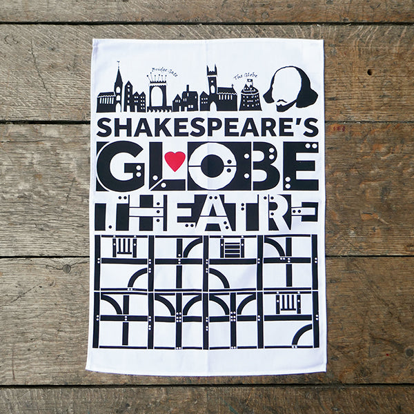 White cotton tea towel printed with black representations of timber-framed panels and the words Globe Theatre. There is a red heart printed in the middle