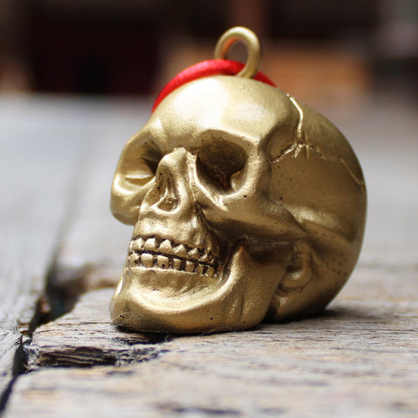 
                      
                        Gold plaster skull decoration with rope tie, on wooden floor
                      
                    