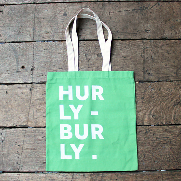 Green cotton bag with a white handle and a typographic print in off white