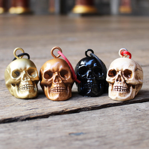 
                      
                        Four plaster skull decorations sitting on wooden floor, from left to right, gold, copper, black, bone
                      
                    