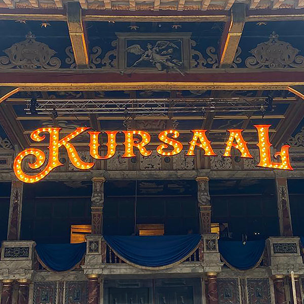Plywood light-up sign spelling KURSAAL on a theatre stage