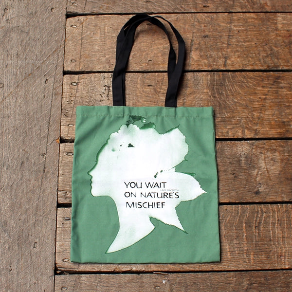 
                  
                    Green bag with black handles and a white print shaped like a woman's head
                  
                