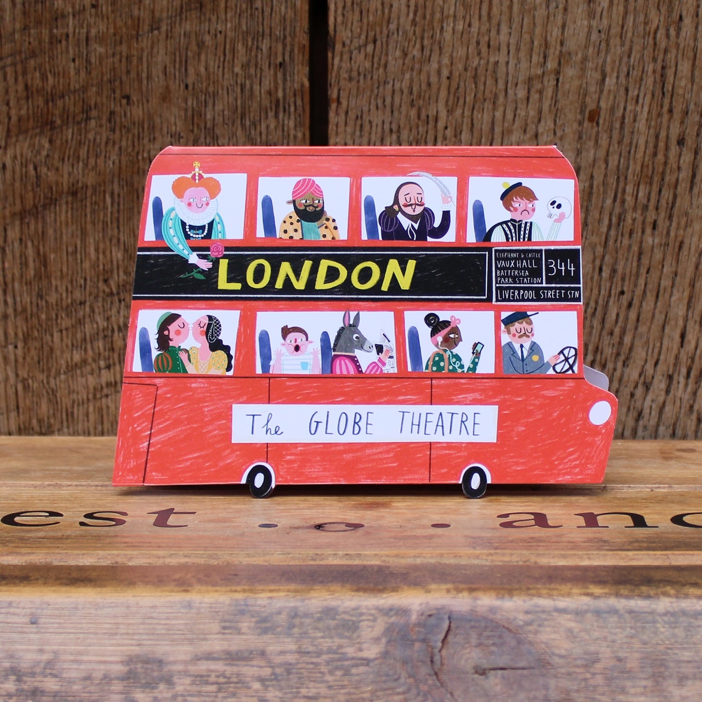 Greetings card shaped like a red London bus with various characters at the windows