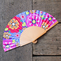 Colourful hand fan with floral designs on a wooden surface