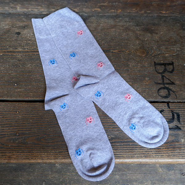 Light grey socks with a repeating pattern of theatre masks in blue and pink