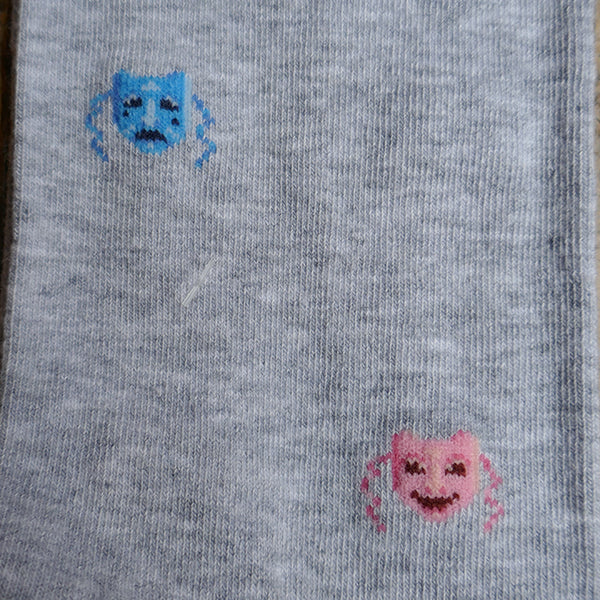 Light grey socks with a repeating pattern of theatre masks in blue and pink