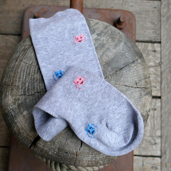 
                  
                    Light grey socks with a repeating pattern of theatre masks in blue and pink
                  
                
