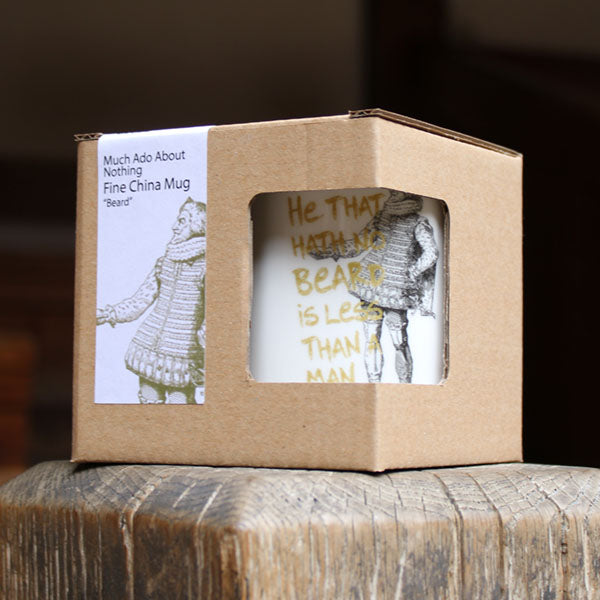 Cardboard box with a window displaying a mug and a quote, on a wooden surface.